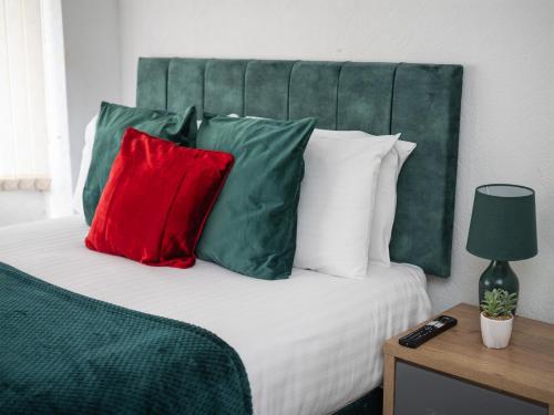 a bed with red and green pillows on it at Spacious 3BR Home with Driveway Near NEC & Airport in Birmingham