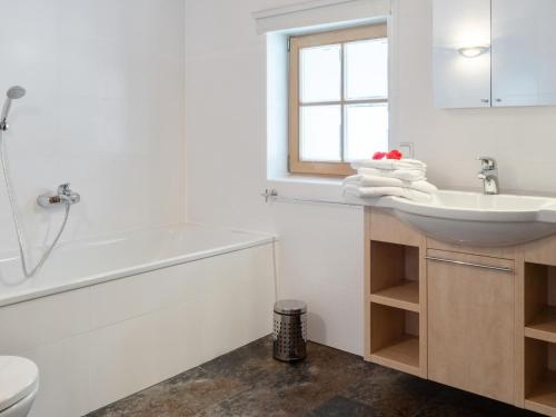 a white bathroom with a sink and a bath tub at Maxima - Ski in - Ski Out in Flecken