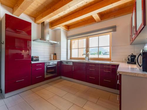 a kitchen with red cabinets and a window at Maxima - Ski in - Ski Out in Flecken