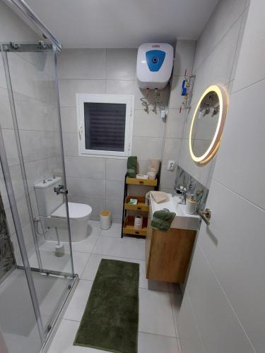 Un baño con ducha, lavabo y espejo. en Vico Holiday Homes 1 Apartman, en Las Medianias