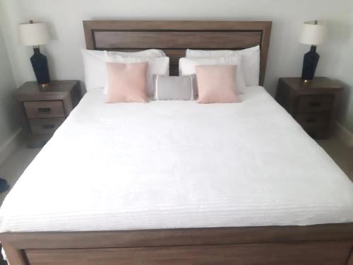 a bedroom with a large white bed with pink pillows at Tropical Bliss Haven in Kingston