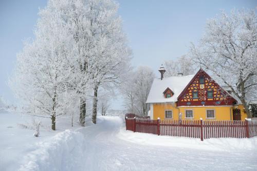 a yellow house with a fence in the snow at Hrazdeny statek Mytinka in Mýtinka