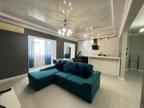 a living room with a blue couch and a kitchen at Апартаменты 2 комнатная возле теннисного центра in Aktobe