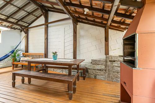a patio with a table and a bench and a stove at Recanto das Palmeiras in Guarda do Embaú