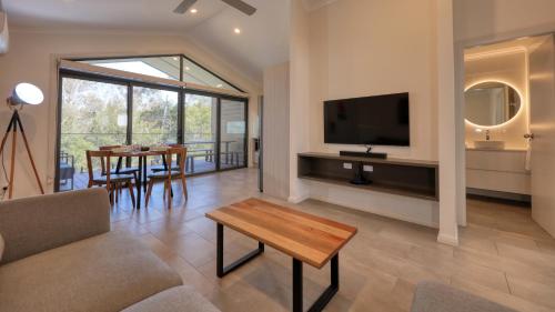 a living room with a couch and a tv and a table at Alivio Tourist Park Canberra in Canberra