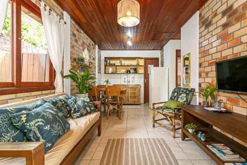 a living room with a couch and a tv and a kitchen at Recanto das Palmeiras in Guarda do Embaú