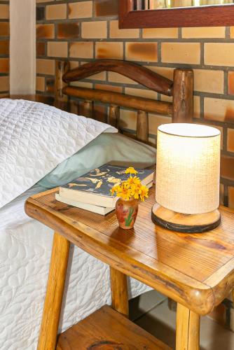 a table with a lamp and a book on a bed at Recanto das Palmeiras in Guarda do Embaú