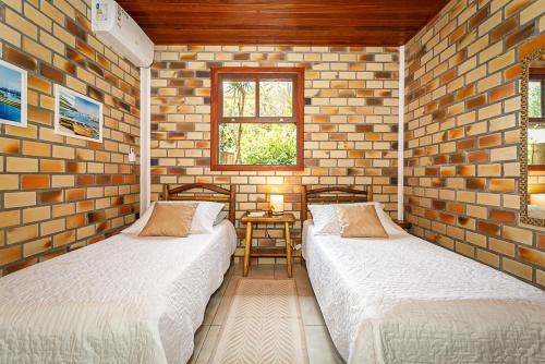 two beds in a room with a brick wall at Recanto das Palmeiras in Guarda do Embaú