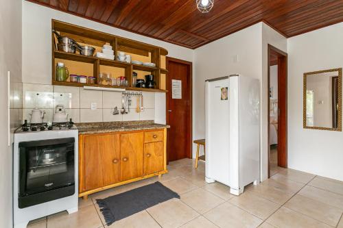 a kitchen with a white refrigerator and wooden cabinets at Recanto das Palmeiras in Guarda do Embaú