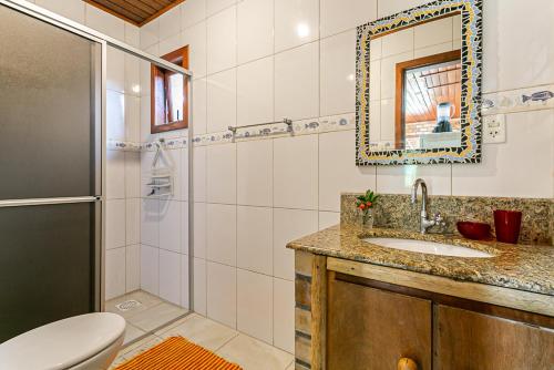 a bathroom with a sink and a toilet and a mirror at Recanto das Palmeiras in Guarda do Embaú