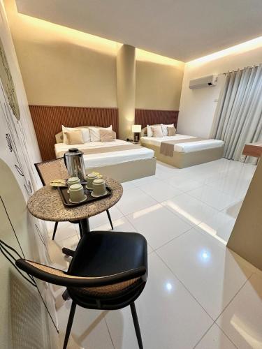a room with two beds and a table with a chair at Hotel Nicanor in Dumaguete