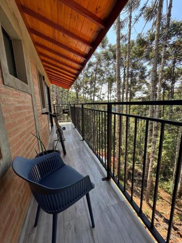 a porch with a bench and a balcony with trees at Espaço RAVI 1 in Monte Verde