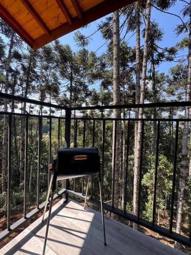 a black chair sitting on a porch with trees at Espaço RAVI 1 in Monte Verde