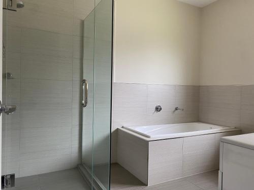 a bathroom with a tub and a glass shower at Sunny House in Auckland