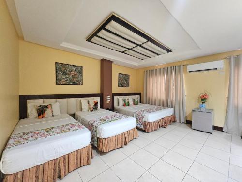 two beds in a room with yellow walls at Hotel Nicanor in Dumaguete