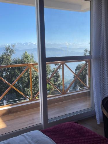 a bedroom with a window with a view of the mountains at Maatidera Resort Kanatal The Boutique stay in the Lap of Himalayas in Kanatal