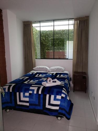 a bedroom with a blue and white bed and a window at Hospedaje El Paraiso in Santa Eulalia
