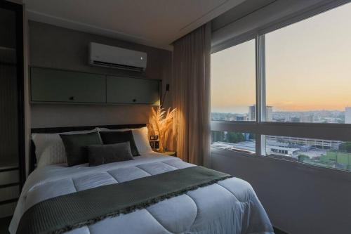 a bedroom with a large bed and a large window at Alexa, Piscina, Aconchegante, Netflix, Gym, Vagas in Porto Alegre