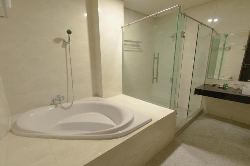 a white bathroom with a shower and a sink at De Balen Soultan Hotel in Puyung