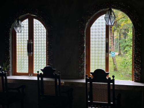 two arched windows in a room with chairs at Krui Surfing in Wainapal