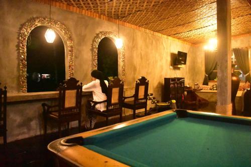 a woman sitting in a room with a pool table at Krui Surfing in Wainapal
