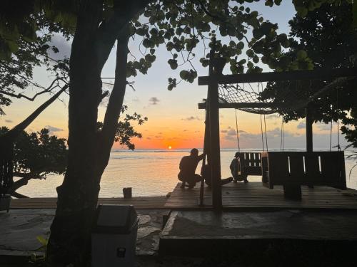 a man sitting on a swing at the beach at sunset at Krui Surfing in Wainapal