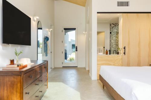 a bedroom with a bed and a tv on the wall at Blackhaus Suites by AvantStay Modern Comfort in Downtown Palm Springs in Palm Springs