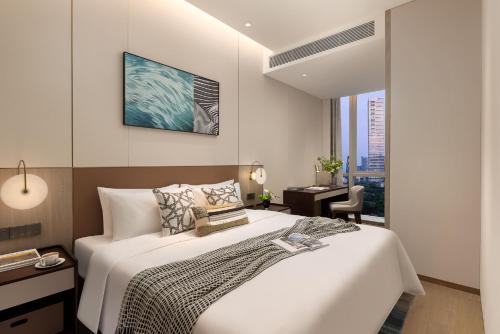 a bedroom with a large white bed and a window at Somerset QPlex Shenzhen in Shenzhen