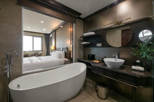 a bathroom with a large white tub and a sink at Ninh Binh Legend Hotel in Ninh Binh