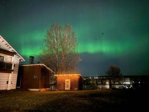 an aurora over a house and a tree in a yard at Arctic River Chalet in Rovaniemi