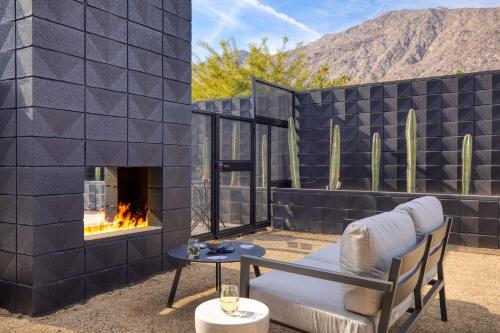 a patio with a fireplace and a chair and a table at Blackhaus Suites by AvantStay Modern Comfort in Downtown Palm Springs in Palm Springs