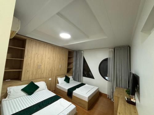 a small room with two beds and a tv at Cat Ba Madame Duyen Hotel in Cat Ba