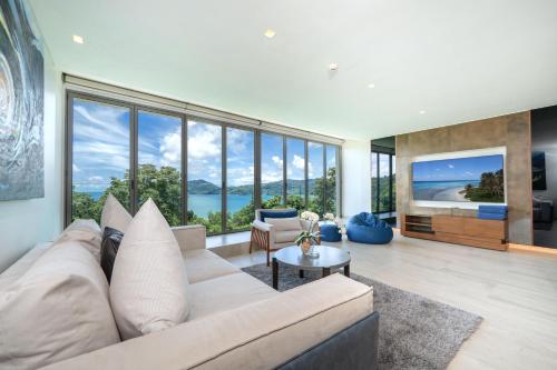a living room with a white couch and large windows at Ocean Bliss - Sapphire Bay 3BR Apartment 812 with Terrace and Awe-Inspiring Views of Patong Bay in Patong Beach