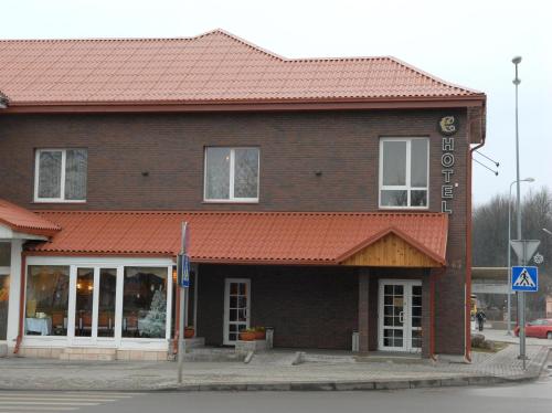 a brown brick building with a red roof at Hotel Centras in Šakiai