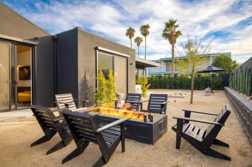 a patio with chairs and a fire pit in front of a house at Blackhaus Suites by AvantStay Modern Comfort in Downtown Palm Springs in Palm Springs