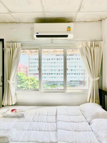 a bedroom with a large white bed and two windows at LSN Mansion in Bangkok