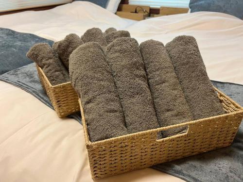 a wicker basket filled with grey towels on a bed at 旅の宿hitotoki in Tokyo