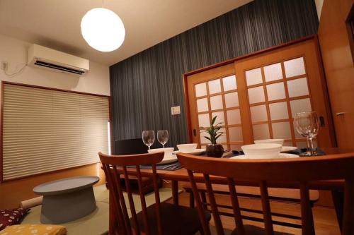 a dining room with a table with chairs and wine glasses at 旅の宿hitotoki in Tokyo