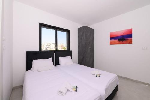 a bedroom with two beds with white sheets at לוי-קיישן מגוון דירות גן ופנטהאוזים וסוויטות נוף ברחוב הצנחנים in Tiberias
