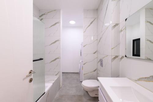 a white bathroom with a toilet and a sink at לוי-קיישן מגוון דירות גן ופנטהאוזים וסוויטות נוף ברחוב הצנחנים in Tiberias