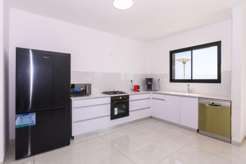 a kitchen with a black refrigerator and white cabinets at לוי-קיישן מגוון דירות גן ופנטהאוזים וסוויטות נוף ברחוב הצנחנים in Tiberias