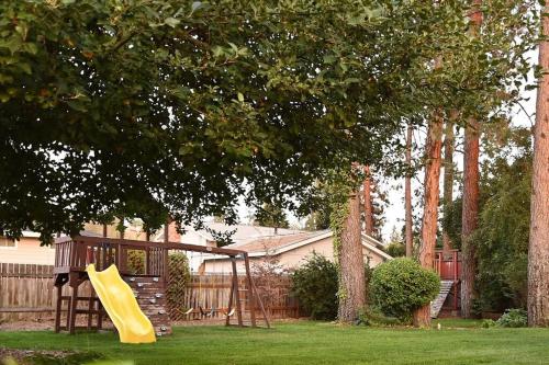 a playground with a yellow slide in a yard at Windsor House in Spokane