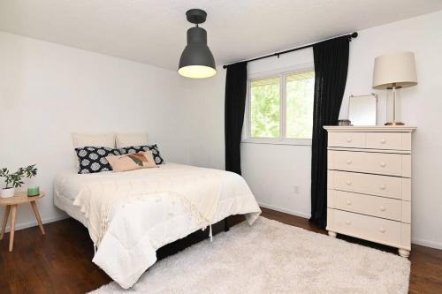 a bedroom with a bed and a dresser and a window at Windsor House in Spokane