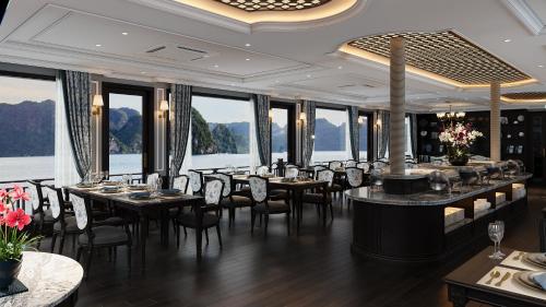 a dining room with tables and chairs and windows at Majesty Luxury Prime Cruise by Premier Group in Ha Long