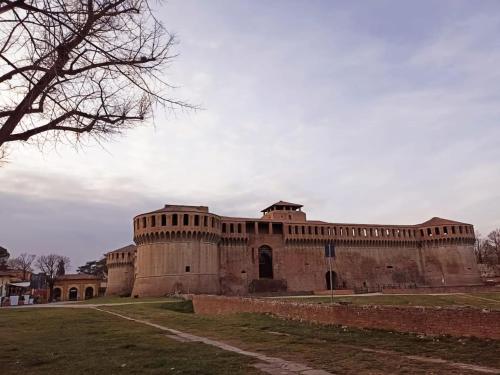 a large brick building with a tree in the foreground at Monnalisa House - Imola Centro Storico - Appartamento Indipendente in Imola