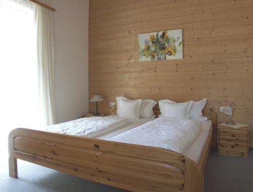 une chambre avec un grand lit avec un mur en bois dans l'établissement Saroja Plus, à Brand