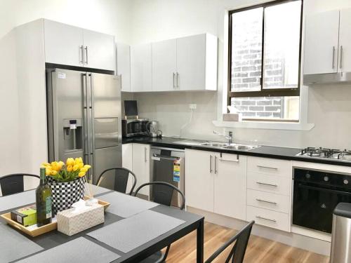 a kitchen with white cabinets and a table with flowers on it at D109 Inner City Oasis on Buckingham in Melbourne