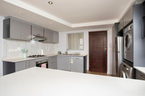 cocina con armarios grises y encimera blanca en Nautica 410 by Mountain City Investments, en Mossel Bay