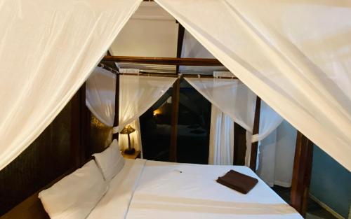 a bedroom with a white bed with white curtains at Village Susegat Beach Resort in Morjim