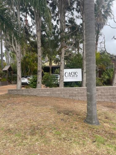 a sign that reads casacs in front of trees at Oasis Inn Ulladulla - Welcoming Guests 18 Years and Older in Ulladulla